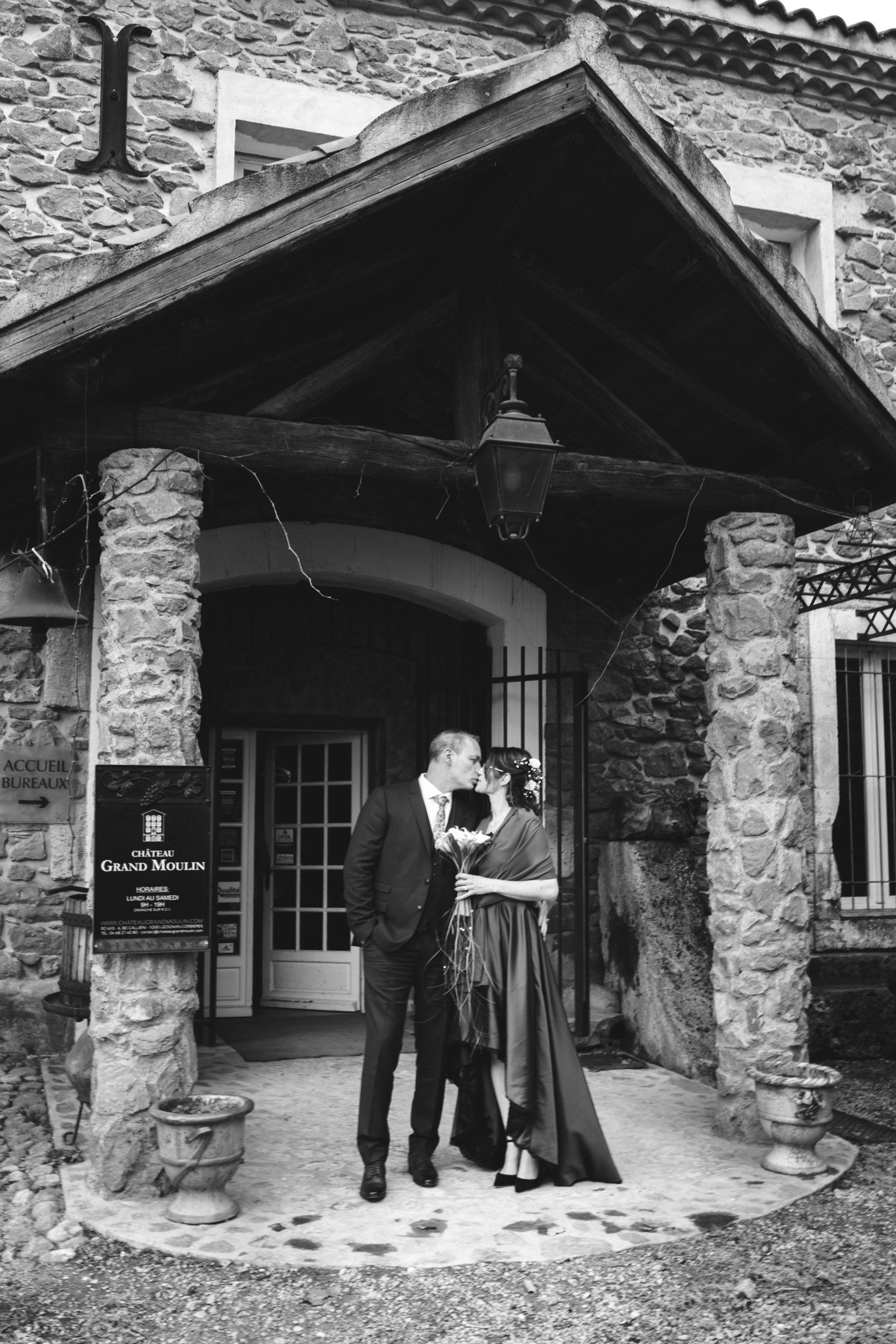 Couple de mariés s'embrassant devant l'entrée du Château Grand Moulin Aude