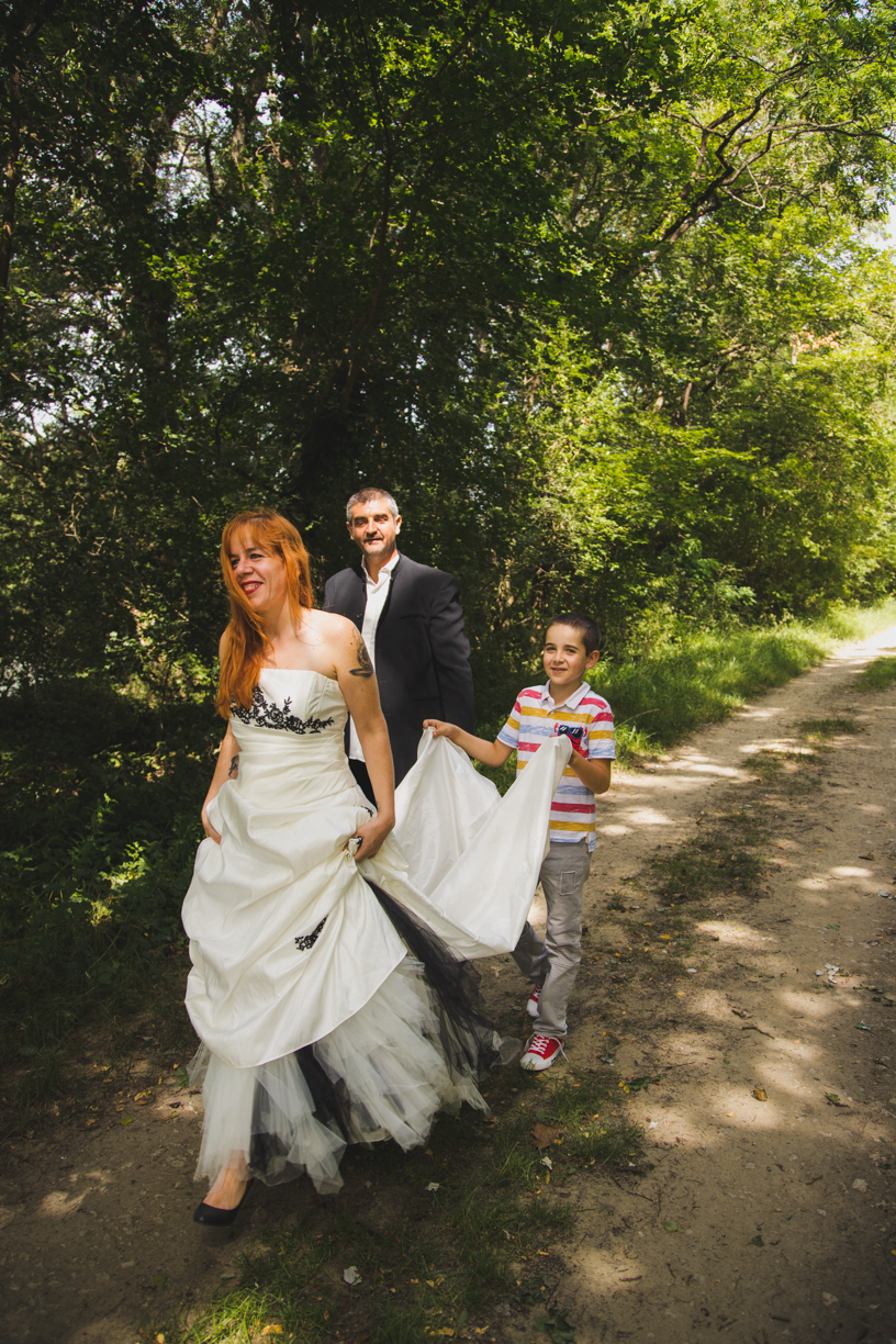 photo de jeune mariés où leur fils tient la traine de la robe