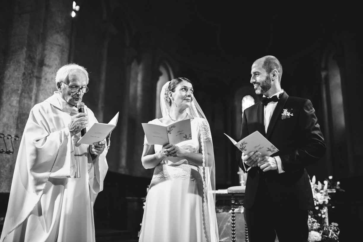 couple de mariés à l'autel, avec le curée, le couple se regarde, photo en noir et blanc